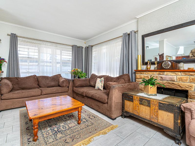 A comfortable living room featuring a prominent stone fireplace, tiled flooring, and large windows that provide ample natural light.