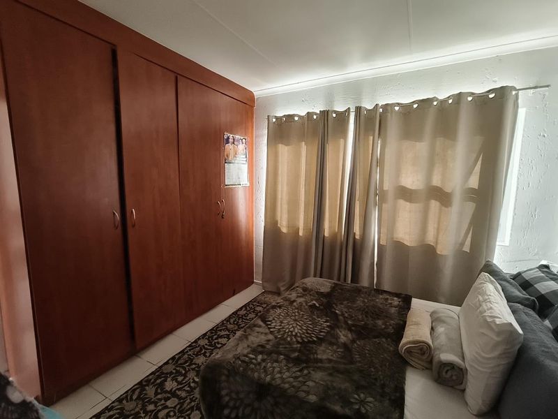 A bedroom featuring built-in wooden cupboards and tiled flooring, providing functional storage space.