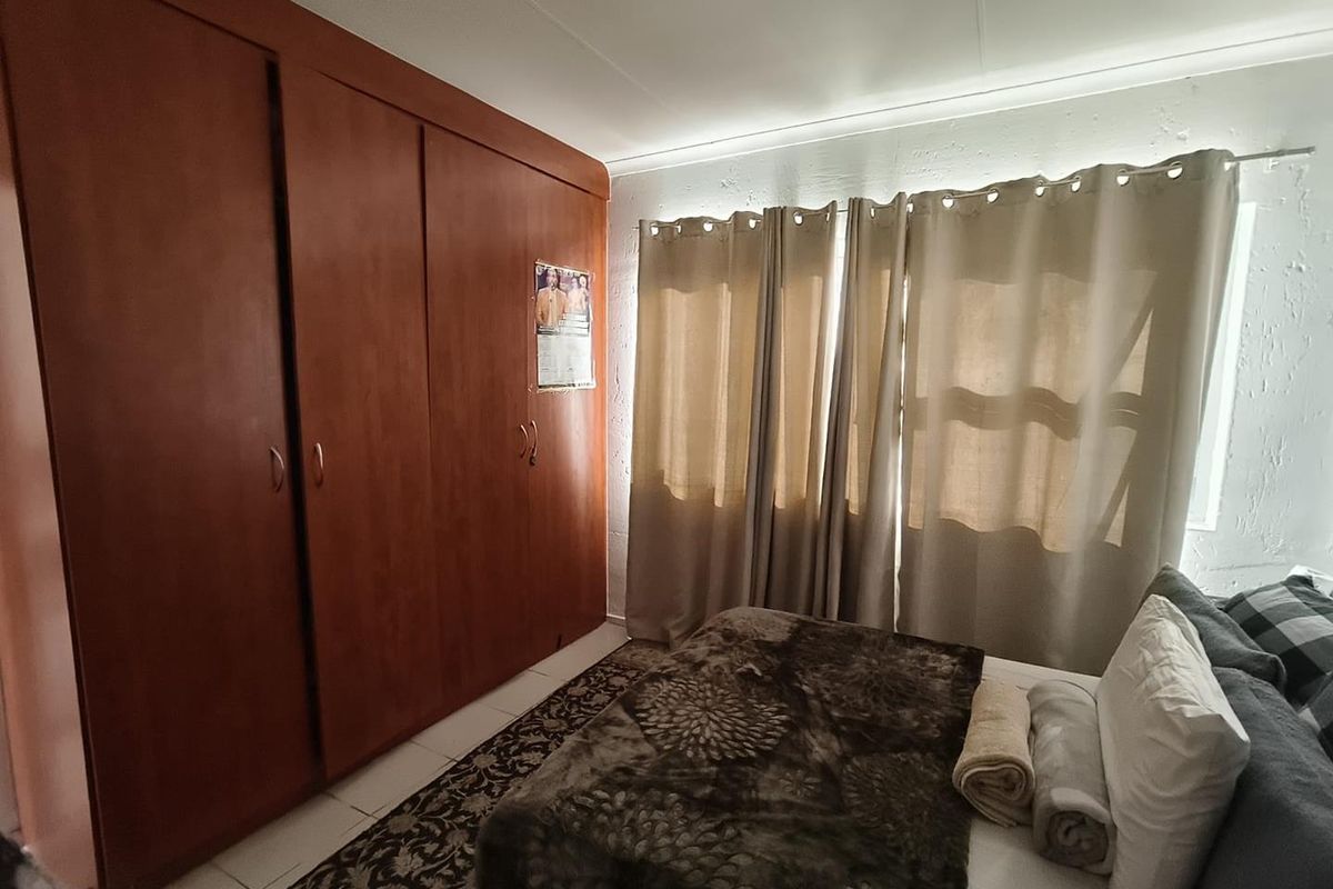 A bedroom featuring built-in wooden cupboards and tiled flooring, providing functional storage space.