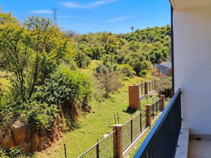 A private balcony featuring a metal balustrade and tiled flooring, offering scenic views of the surrounding natural landscape and greenery.