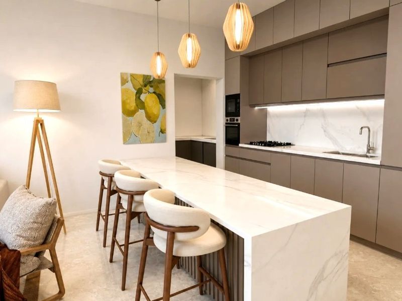 Modern open-plan kitchen featuring a marble island, sleek cabinetry, integrated appliances, and stone flooring, seamlessly flowing into the living area.