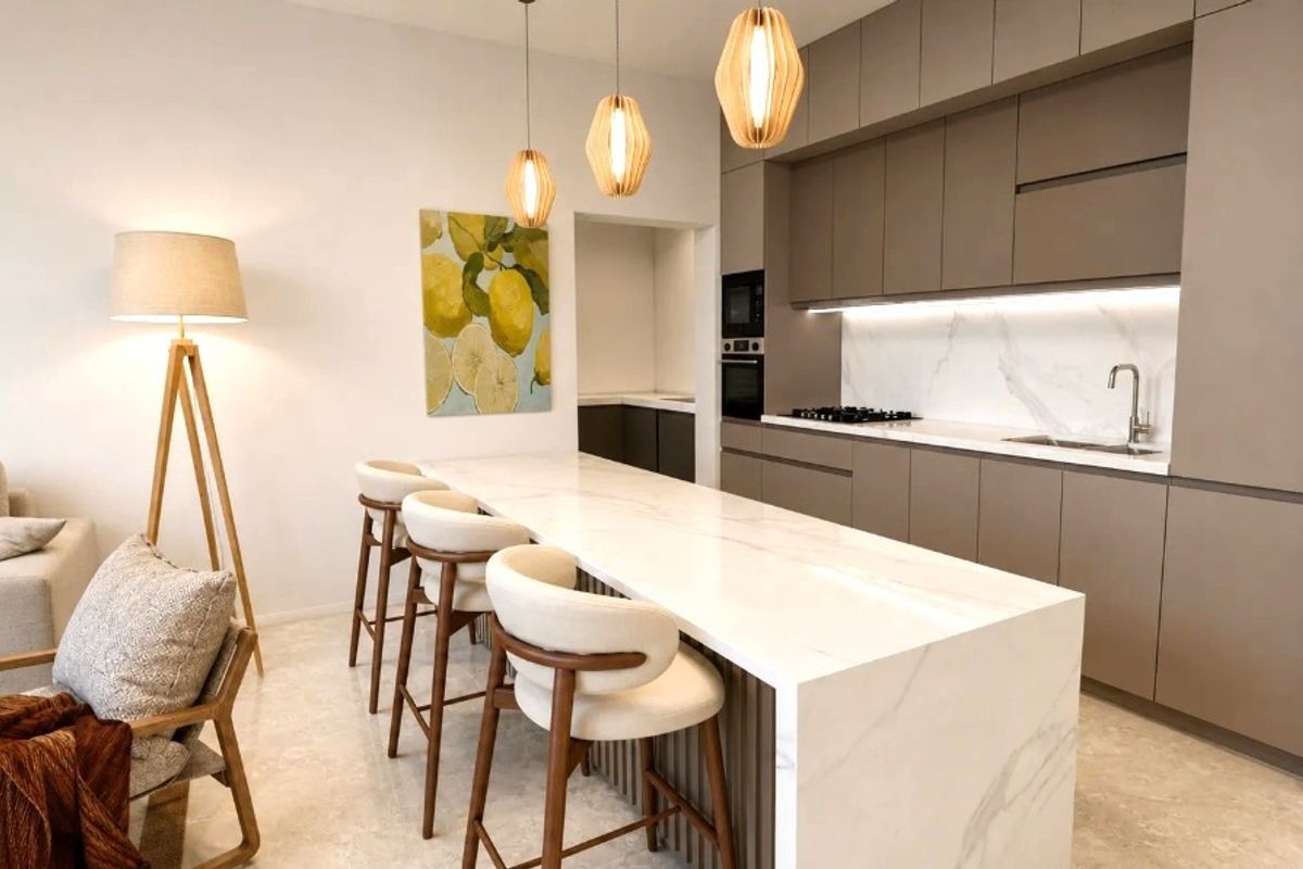 Modern open-plan kitchen featuring a marble island, sleek cabinetry, integrated appliances, and stone flooring, seamlessly flowing into the living area.