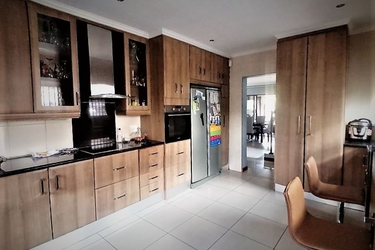 A functional kitchen featuring wood-finish cabinetry, black granite countertops, integrated oven, and tiled flooring, with a seamless transition to the adjacent dining area.
