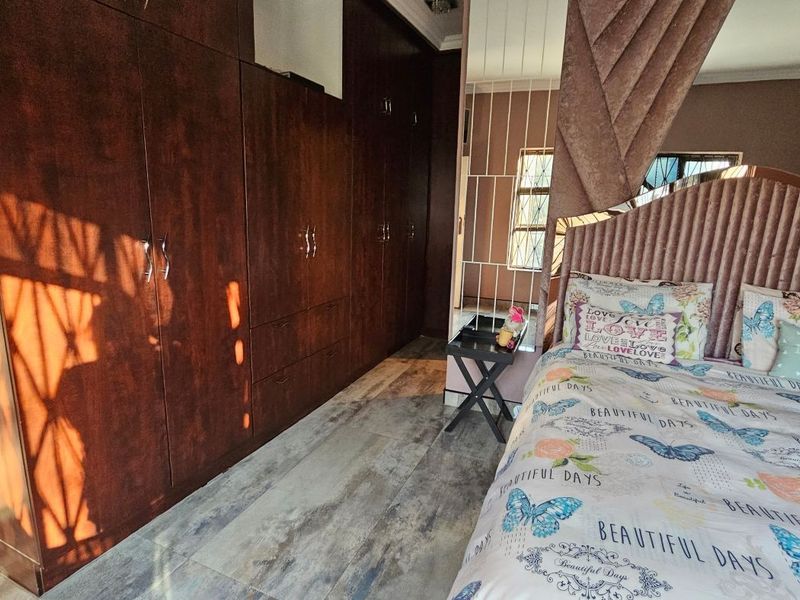 A bedroom featuring extensive dark wood built-in cupboards and modern wood-look tiled flooring.