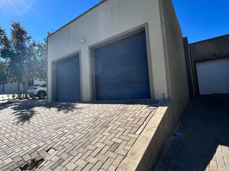 Exterior view of a double garage with a paved driveway and concrete retaining wall structure.