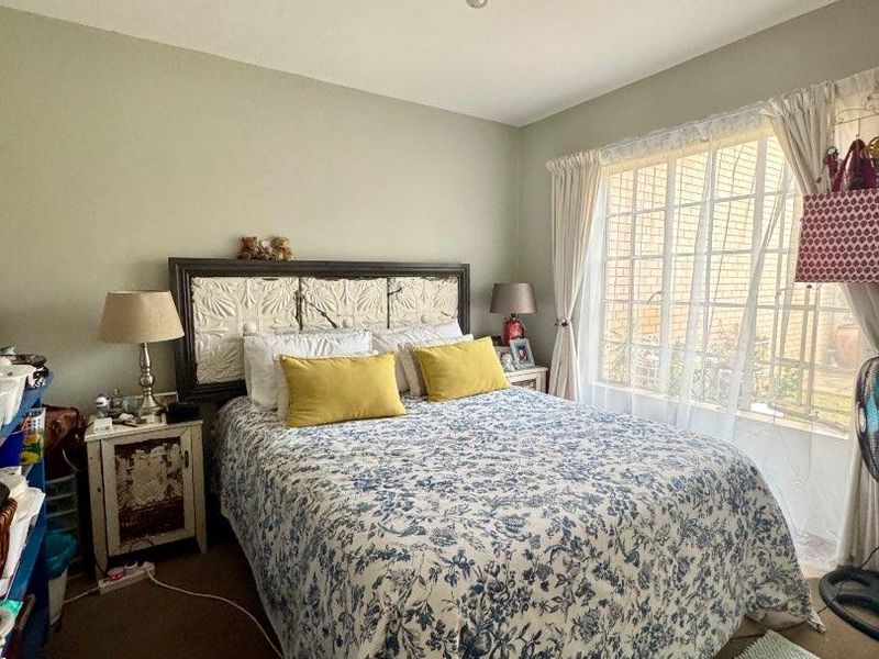 A standard bedroom featuring a window with security bars and a central ceiling light fixture.