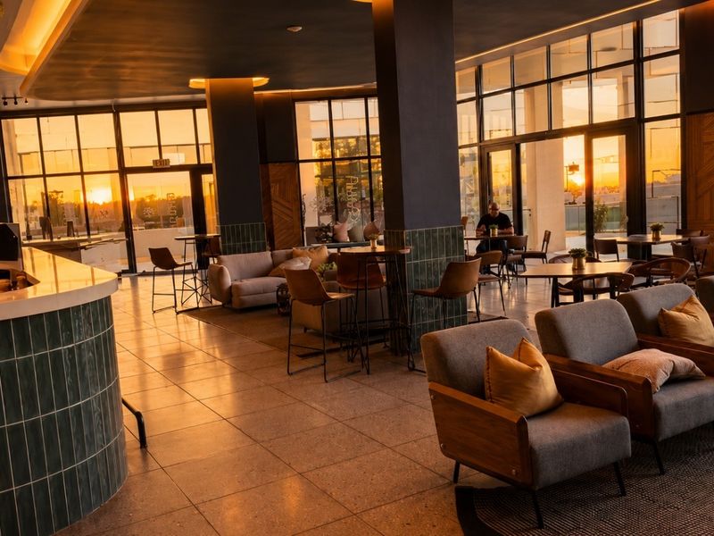 Spacious open-plan living and bar area featuring large floor-to-ceiling windows, modern tiled finishes, and elegant recessed lighting.