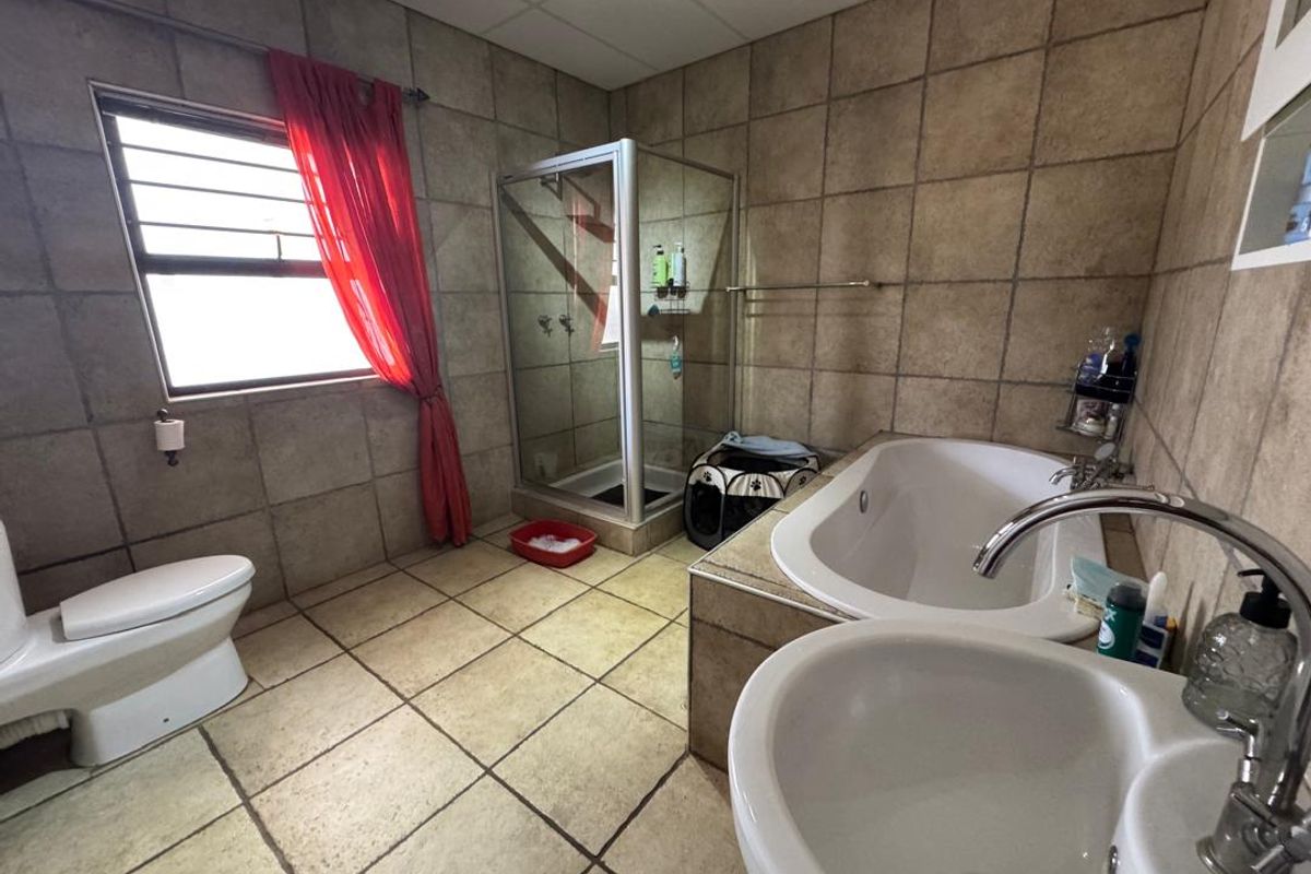 A functional bathroom featuring a shower enclosure, built-in bathtub, pedestal basin, and toilet with neutral tiled finishes throughout.