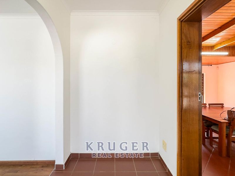 A clean, empty hallway featuring an arched entryway and tiled flooring, providing access to adjacent living spaces.