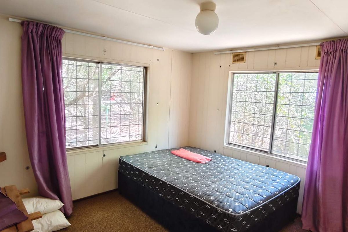 A bedroom featuring timber-look wall paneling, carpeted flooring, and security bars on the windows.