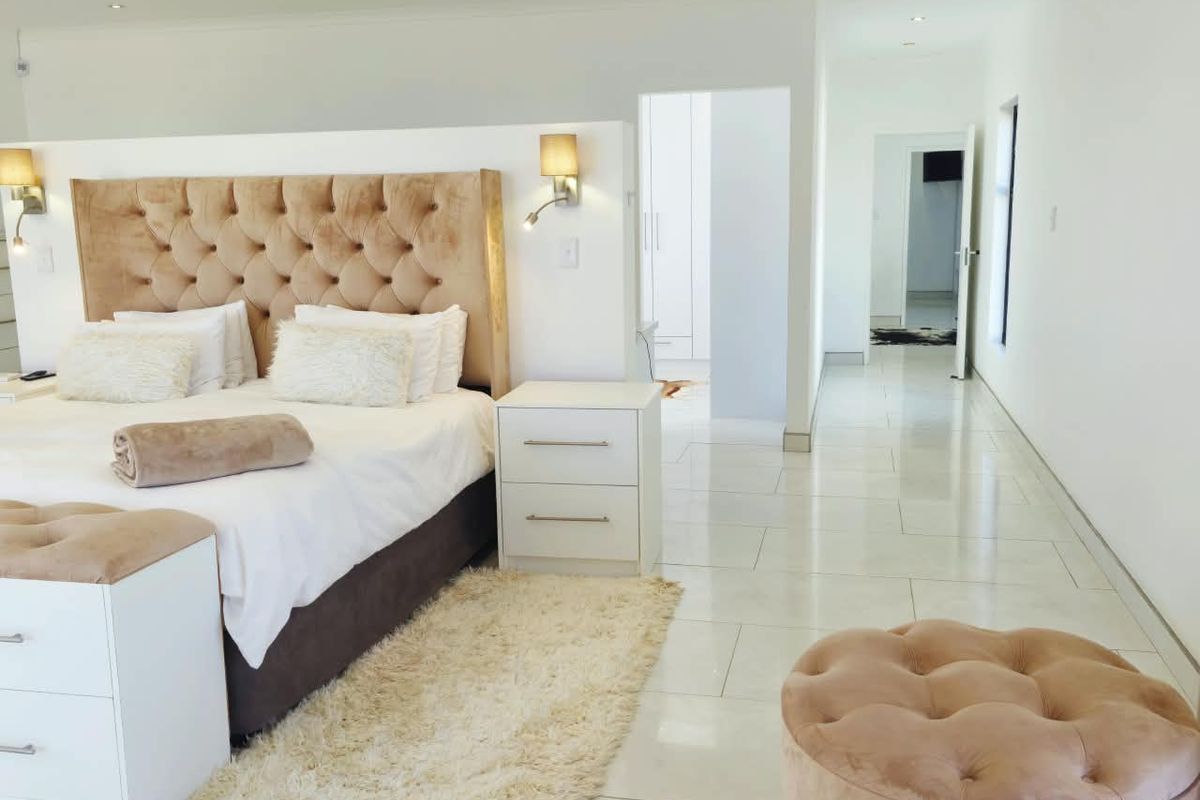 Spacious bedroom featuring polished tiled flooring, recessed downlighting, and a modern layout with an adjoining walk-through area.