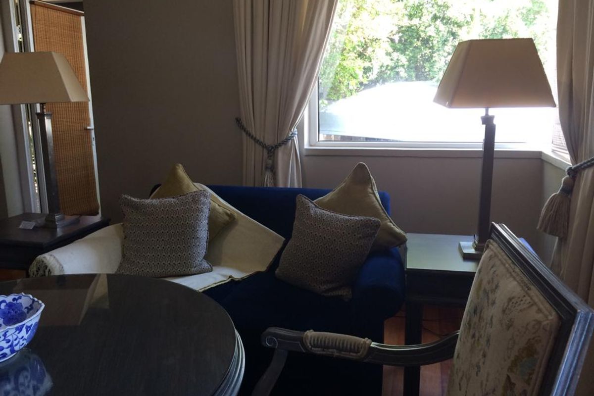 A cozy living room area featuring a bay window with natural light and hardwood flooring.