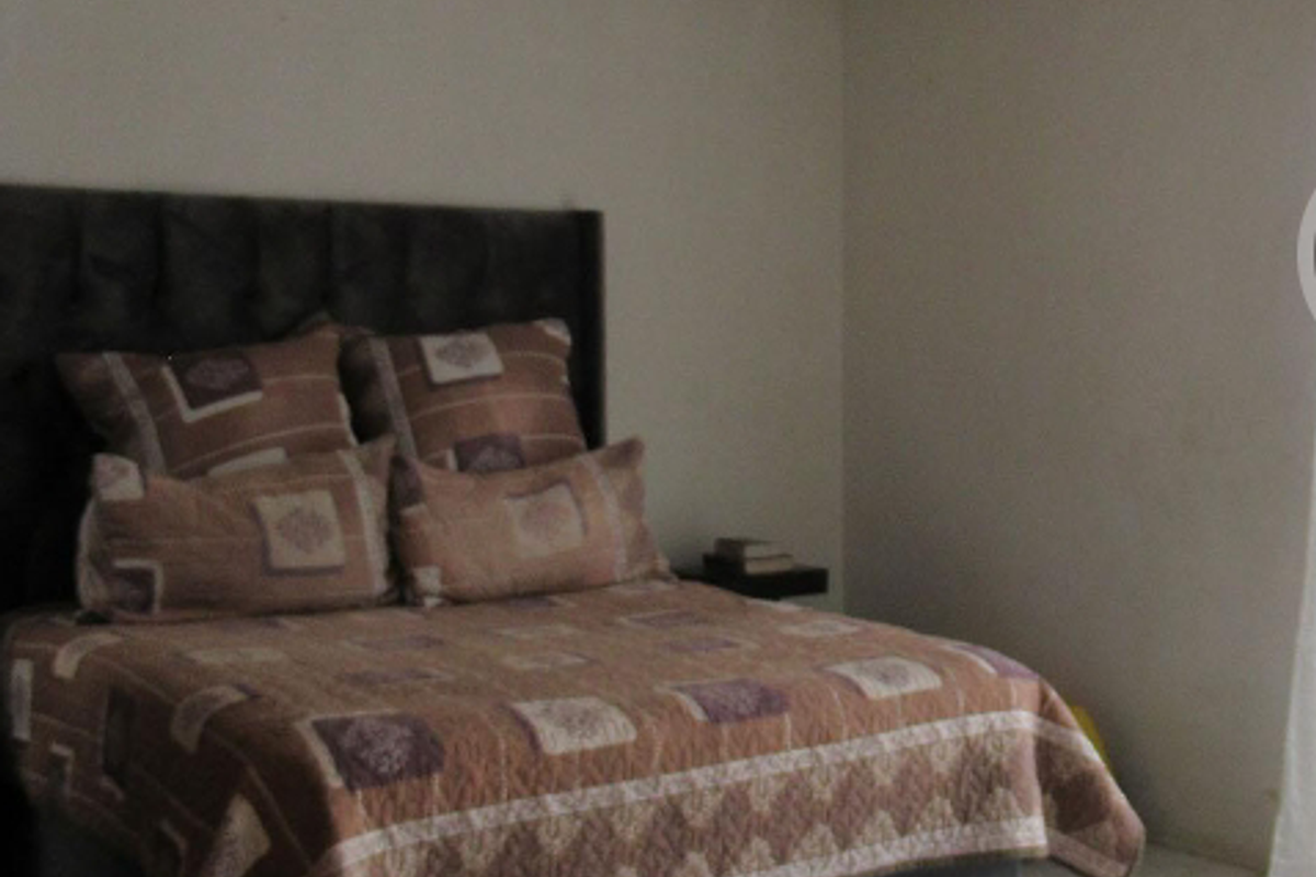 A bedroom featuring tiled flooring and neutral wall finishes, providing a simple and functional living space.