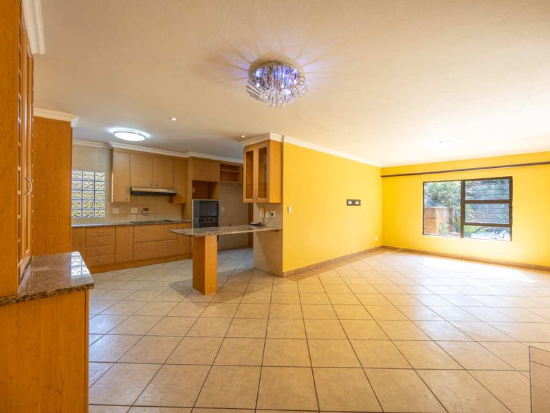Spacious open-plan kitchen and living area featuring wooden cabinetry, granite countertops, tiled flooring, and ample natural light.