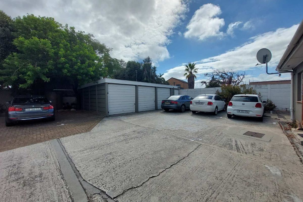 Exterior view of the office property featuring a paved parking area and a multi-bay garage structure with perimeter walling.