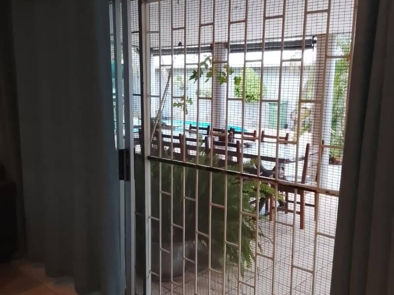 Interior view of a living area featuring a sliding glass door with a security gate leading to an outdoor patio space.