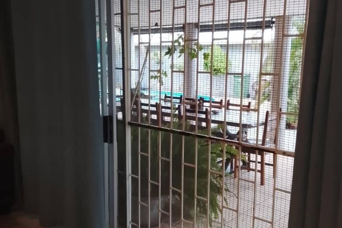 Interior view of a living area featuring a sliding glass door with a security gate leading to an outdoor patio space.