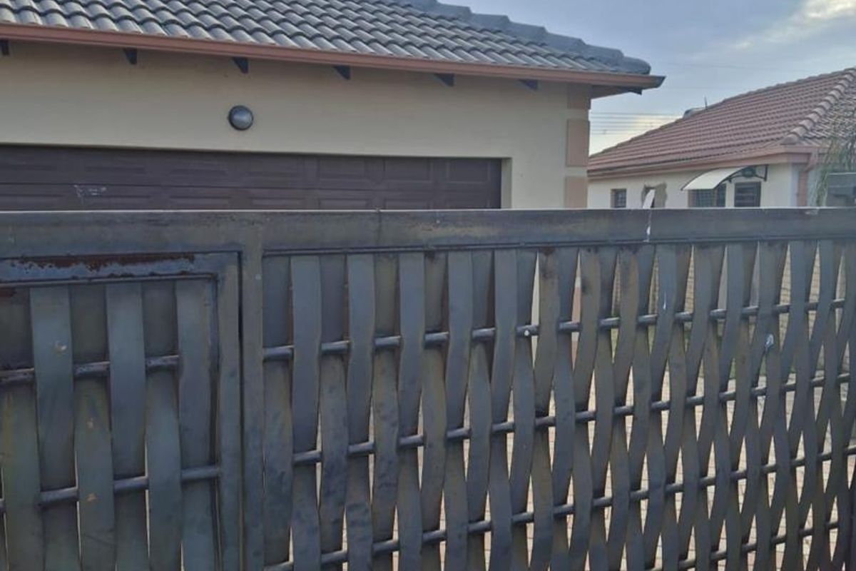 Front view of the property featuring a metal sliding gate, tiled roof, and garage access.