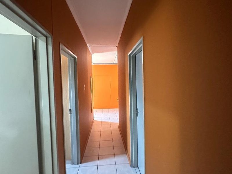 A simple, functional hallway featuring tiled flooring and access to multiple rooms.