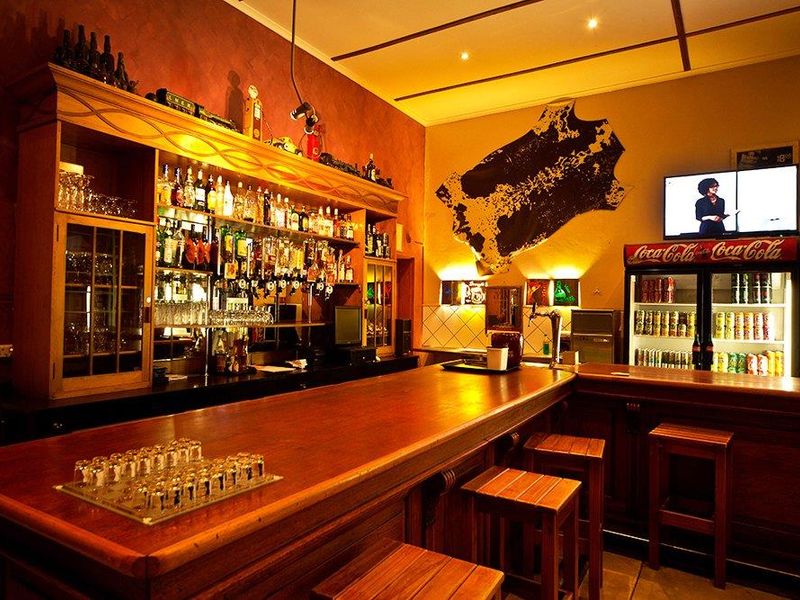 A well-appointed hotel bar featuring a large wooden counter, extensive back-bar shelving, and integrated display refrigeration.