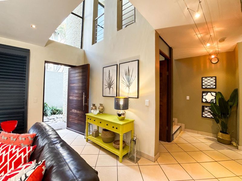 Spacious double-volume entrance hall featuring tiled flooring, recessed lighting, and a timber front door, leading into the main living area and staircase.