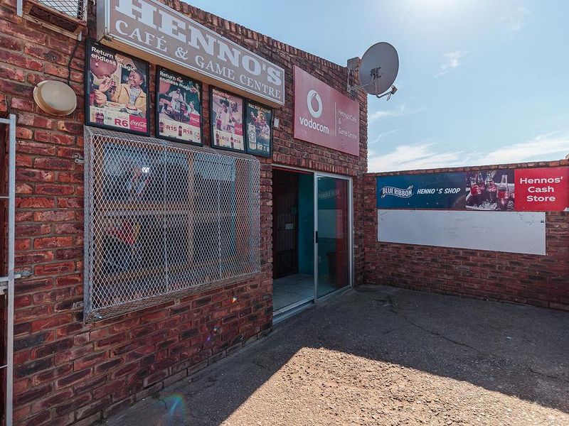Front exterior view of a commercial lodge property featuring exposed brickwork, security gate, and signage for a cafe and game centre.