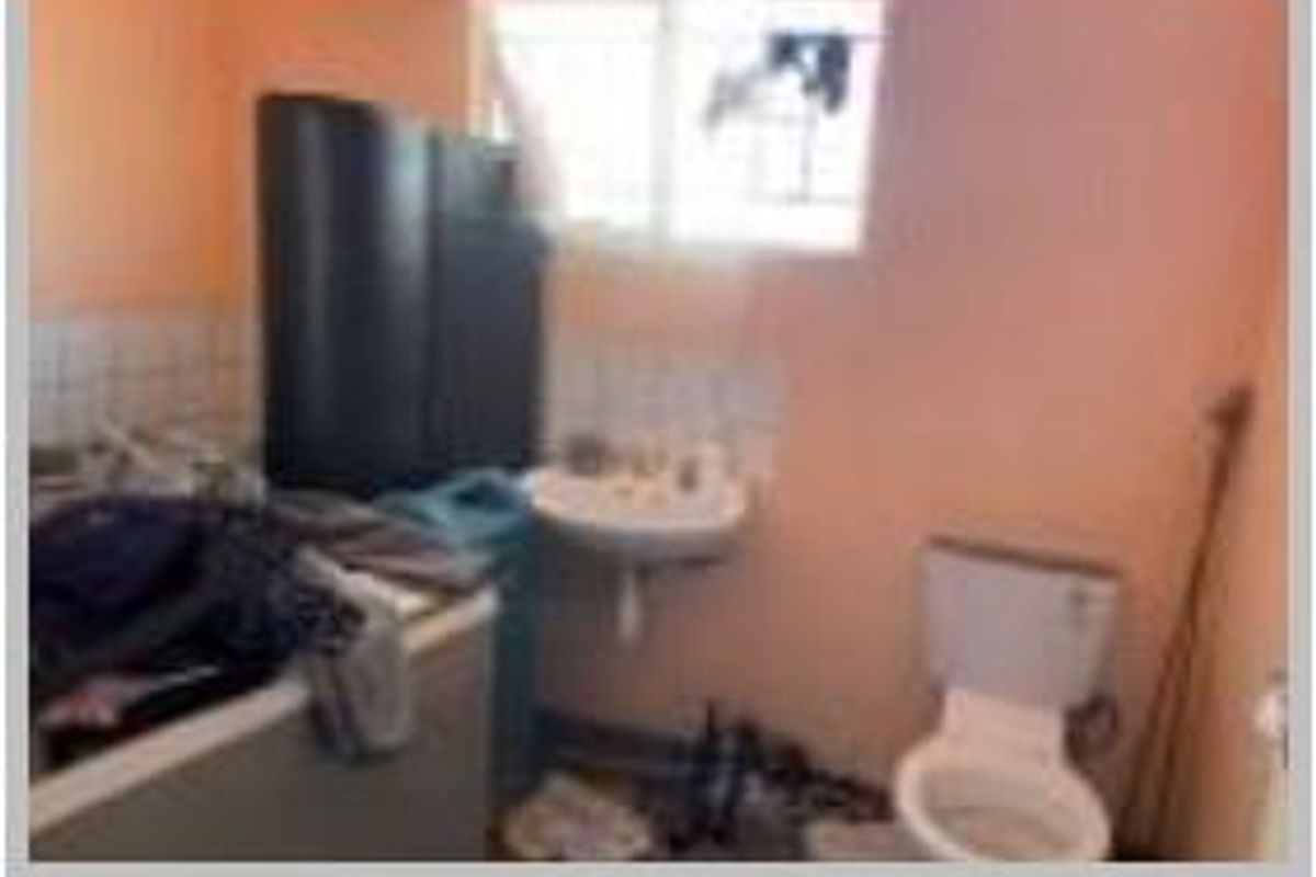 A small bathroom featuring a wall-mounted basin and toilet, requiring significant maintenance and cosmetic updates to improve its overall condition.