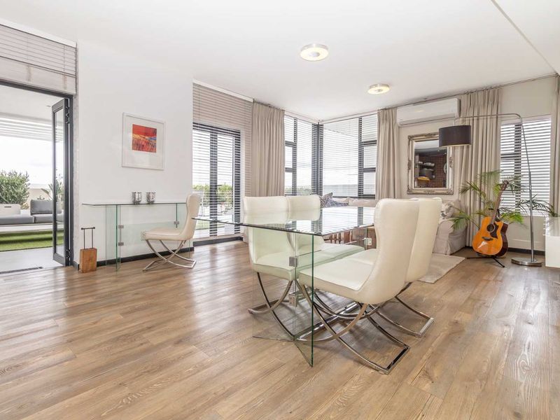 Bright open-plan living and dining area featuring modern laminate flooring, split-system air conditioning, and large windows with access to an outdoor patio.
