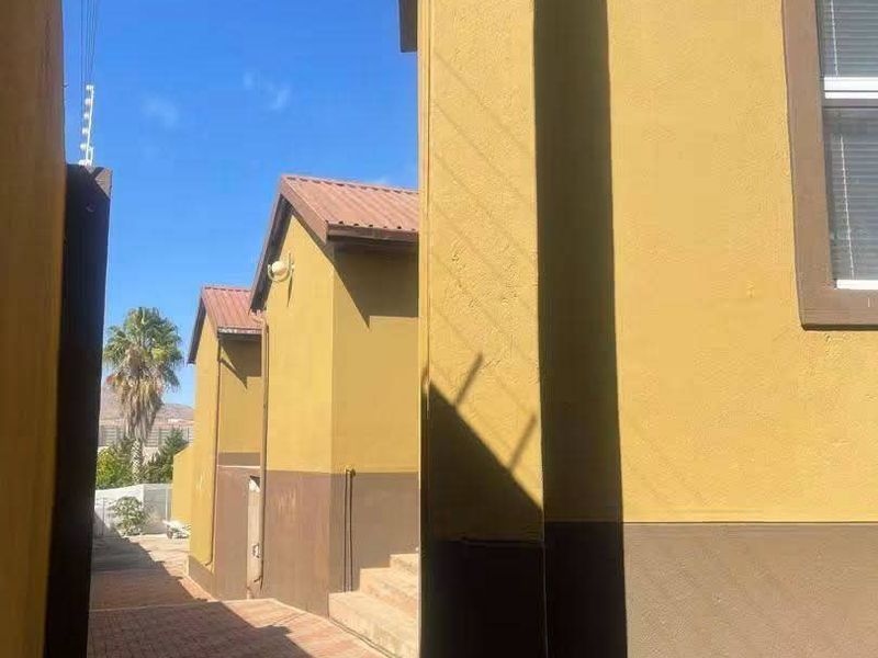 A side passage featuring paved walkways, external security lighting, and access stairs along the exterior of the building.