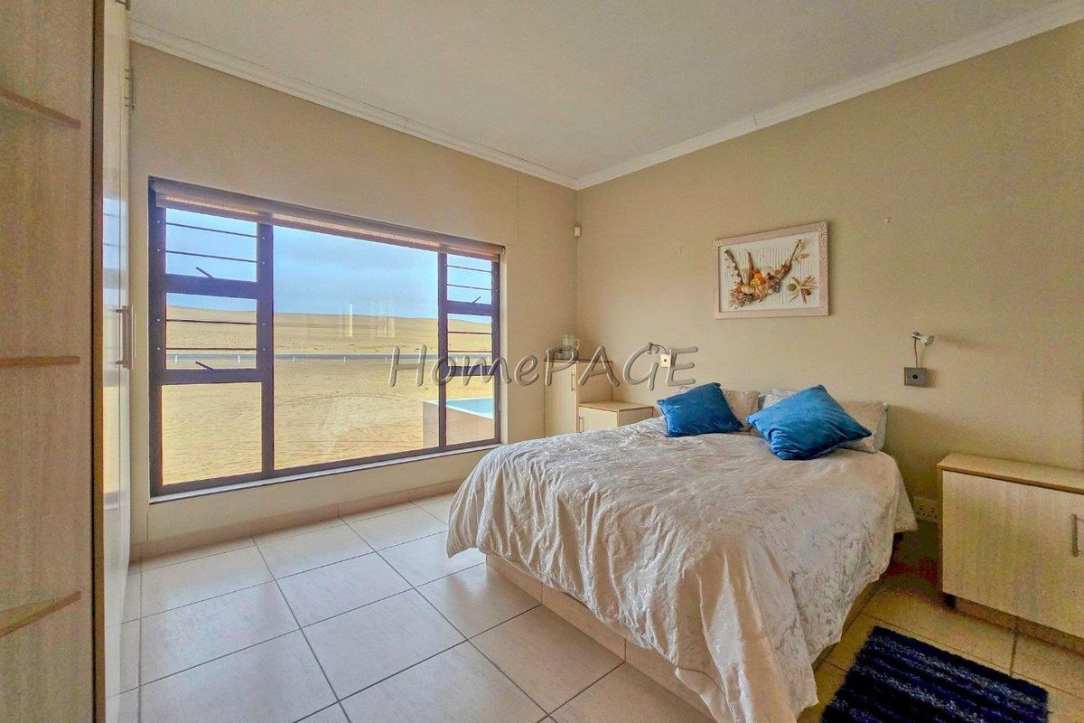 A bright bedroom featuring large windows with coastal views, tiled flooring, and built-in cabinetry.