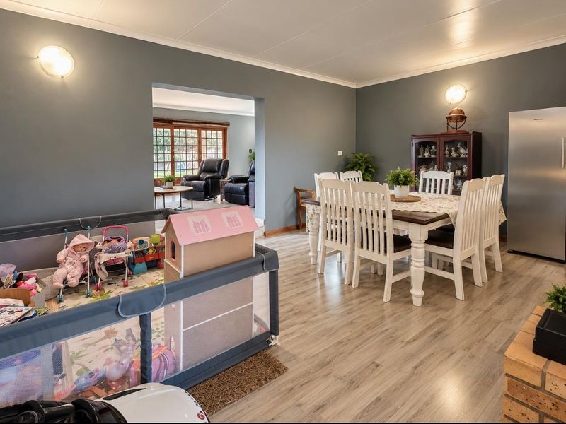 Spacious open-plan dining area featuring laminate flooring and neutral wall tones, with a seamless transition into the adjacent living space.