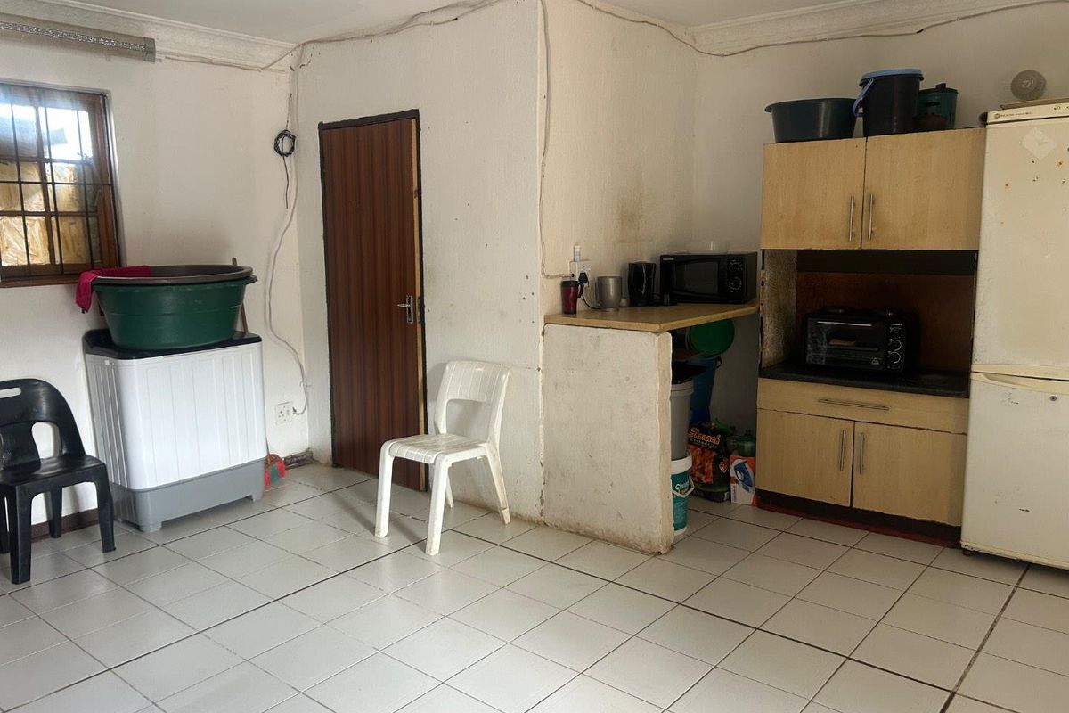 A functional kitchen area featuring tiled flooring, built-in cabinetry, and a dedicated laundry space with plumbing connections.