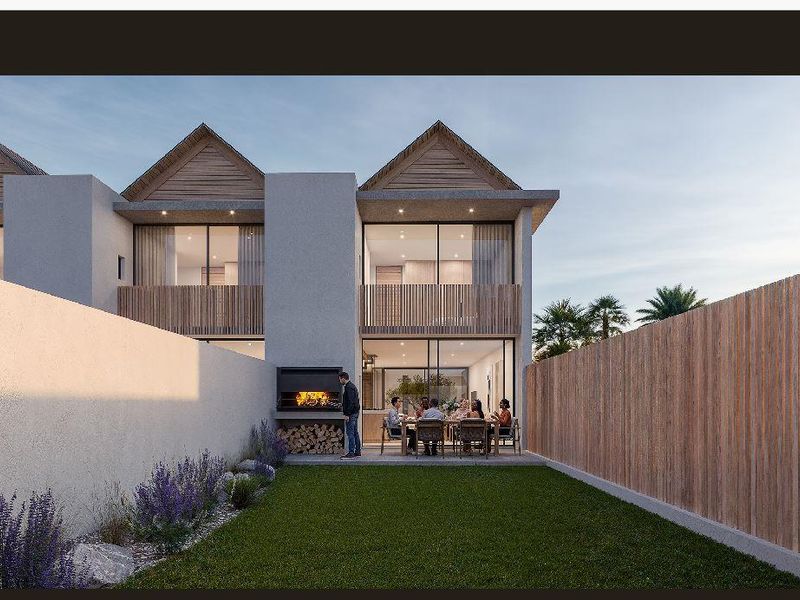 Rear view of a modern townhouse featuring a private garden, paved patio area with a built-in braai, and timber-clad balcony details.