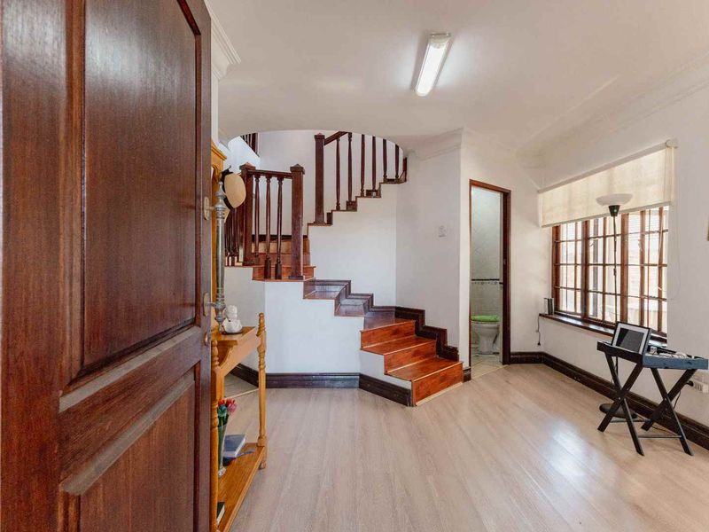 Welcoming entrance hall featuring a classic wooden staircase with balustrade, light laminate flooring, and large windows allowing for natural light.
