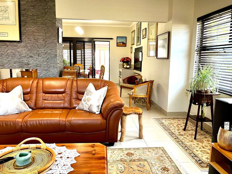 Open plan living area featuring a textured stacked stone feature wall, neutral tiled flooring, and access to an outdoor patio through sliding glass doors.