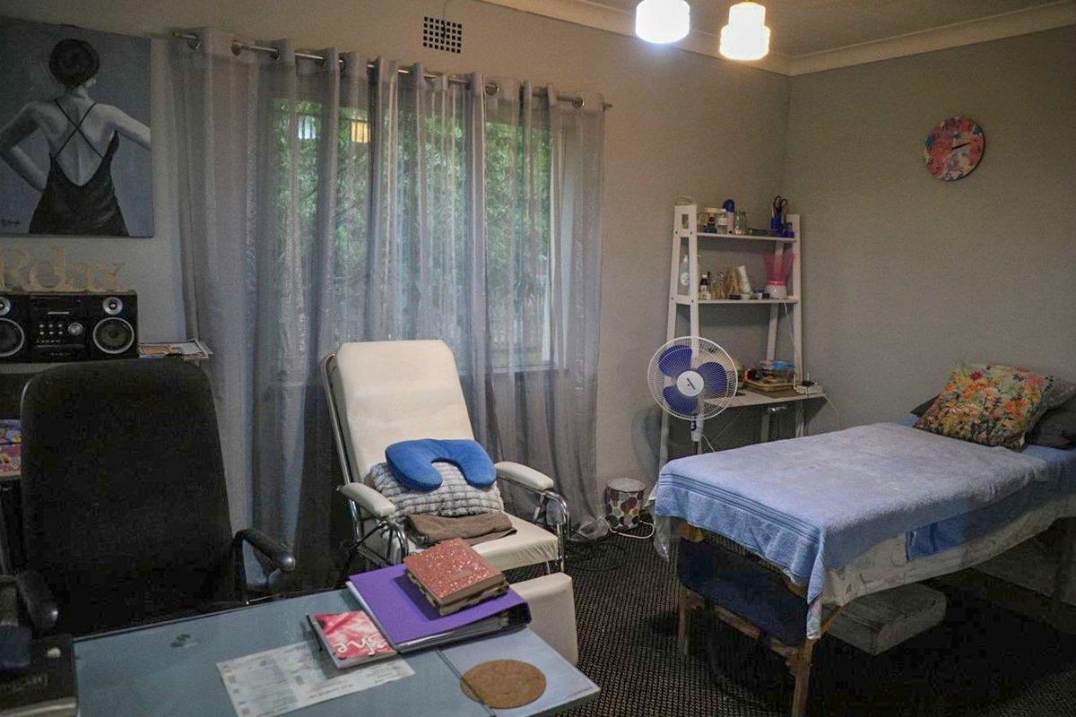 A functional bedroom space featuring neutral wall finishes and a window with curtains, currently utilized as a treatment room.