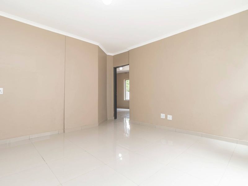 A bright, empty living area featuring neutral wall paint, clean ceramic floor tiles, and modern cove cornicing, ready for personalization.