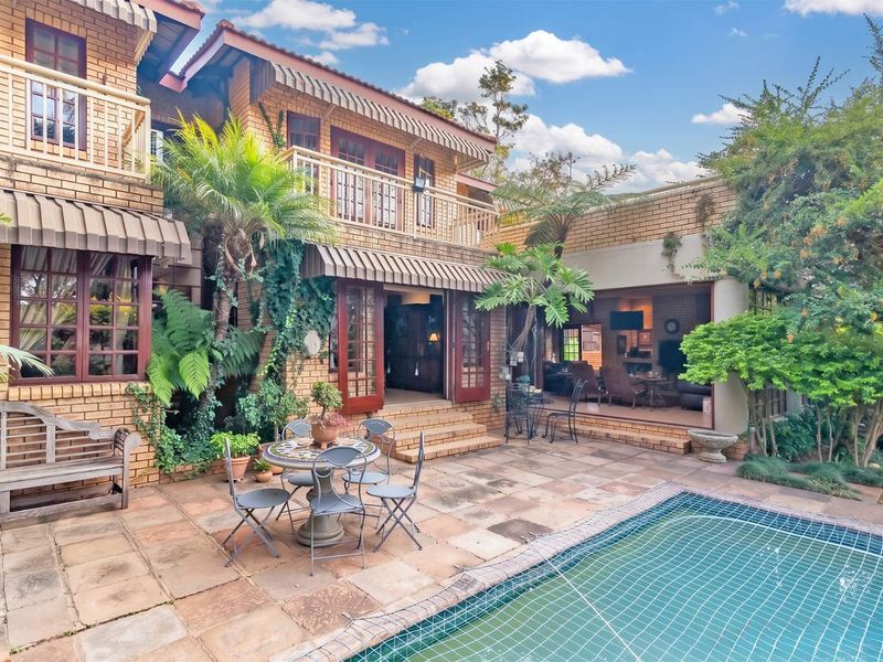 A spacious rear patio area featuring a swimming pool, brick facade, and direct access to the interior living spaces through large glass doors.