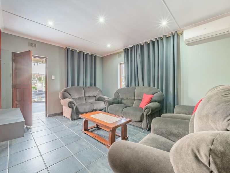A comfortable living room featuring tiled flooring, a stone accent wall, recessed lighting, and a wall-mounted air conditioning unit.