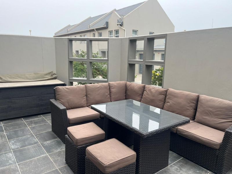 A private outdoor patio area featuring tiled flooring and a solid masonry boundary wall with decorative concrete screen inserts.
