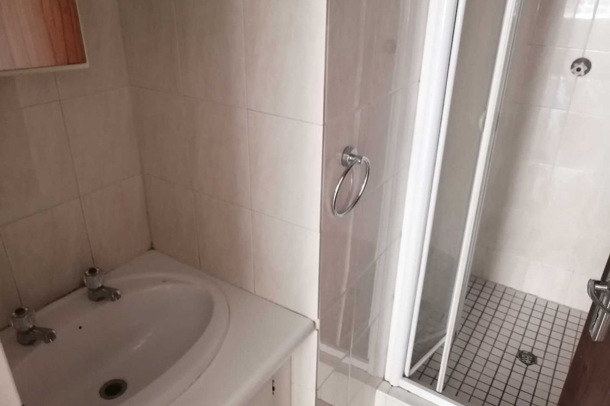 A functional bathroom featuring a built-in vanity basin, tiled walls, and a separate shower enclosure with a glass door.
