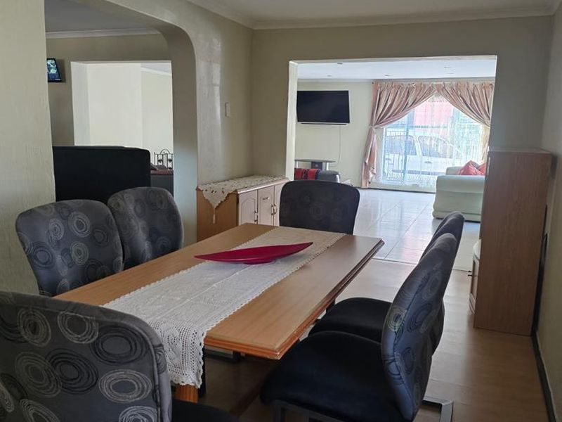 Open plan dining and living area featuring laminate flooring and an arched transition between spaces, offering a functional layout for family living.