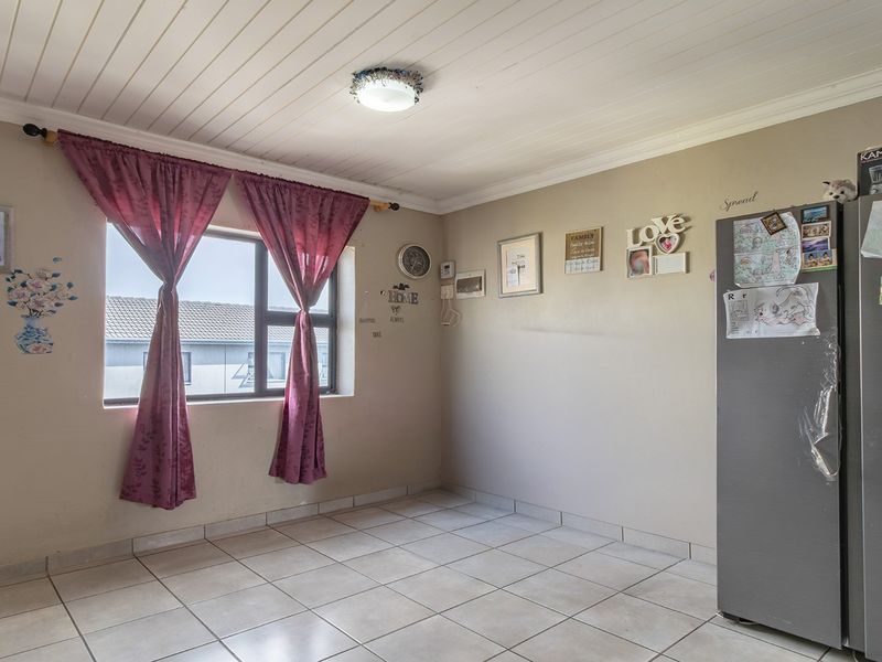 A functional kitchen area featuring tiled flooring and a white tongue and groove ceiling, offering a blank canvas for potential renovation and modernization.