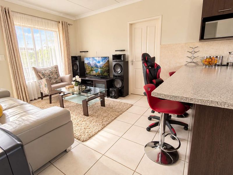 Open-plan living area featuring a modern kitchen with granite countertops and built-in microwave, seamlessly flowing into a bright lounge with balcony access.