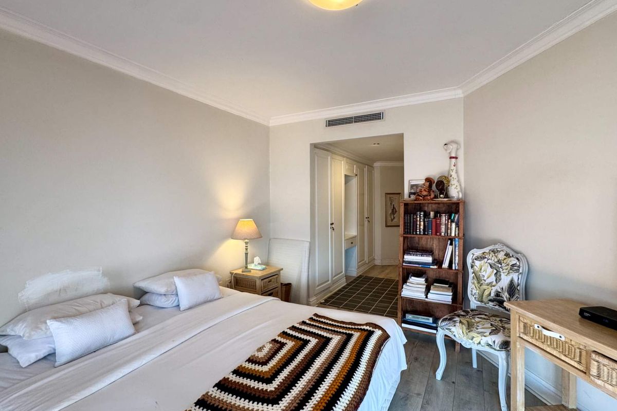A well-proportioned bedroom featuring built-in cupboards, ducted air conditioning, and crown molding, offering a comfortable and functional living space.