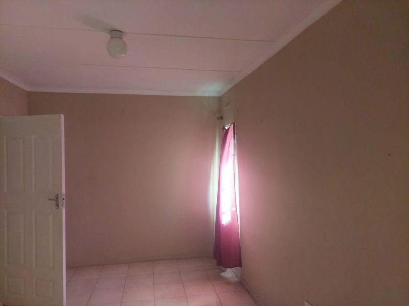 An empty bedroom featuring tiled flooring and neutral wall finishes, offering a blank canvas for potential interior design updates.