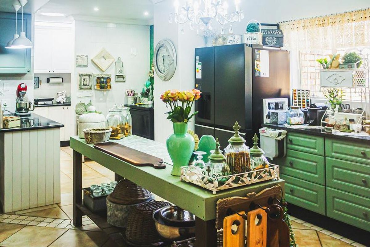 A charming kitchen featuring painted cabinetry, a central island, tiled flooring, and ample counter space, creating a warm and functional culinary environment.