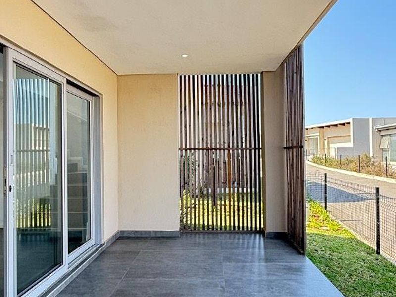 A modern covered patio featuring large format floor tiles, recessed lighting, and a timber slat privacy screen, providing a seamless transition to the outdoor area.