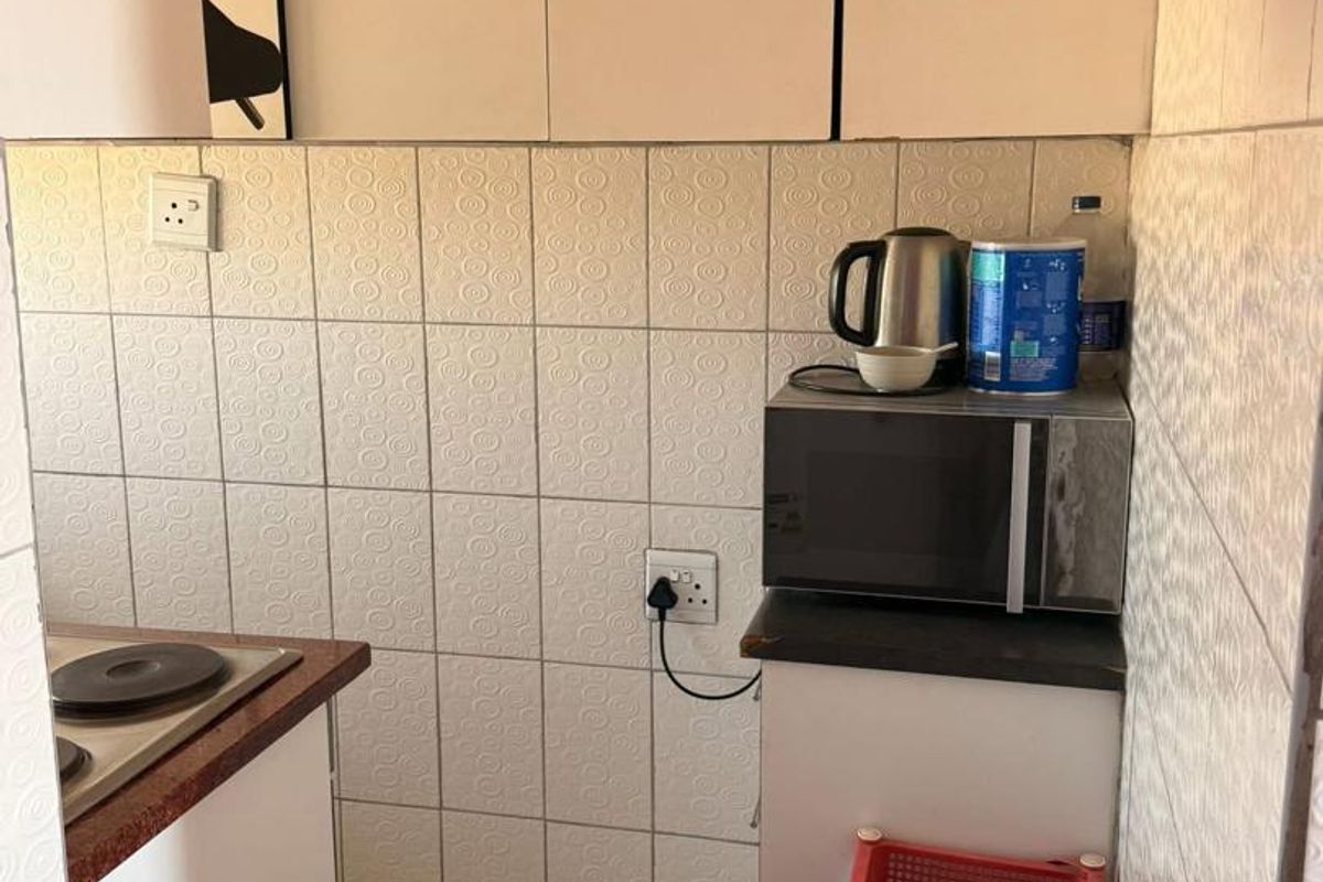 Compact kitchen area featuring built-in cabinetry, tiled walls, and a functional countertop space for food preparation.
