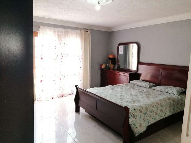A bedroom featuring tiled flooring, decorative ceiling coving, and a sliding glass door providing natural light.